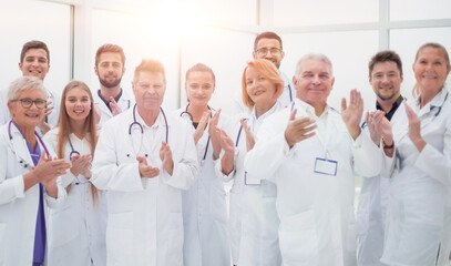 group of diverse smiling doctors applauding together.