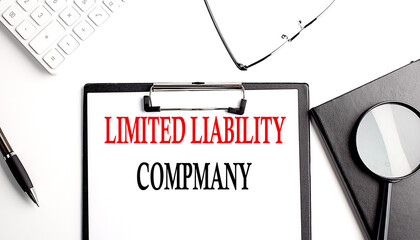 LIMITED LIABILITY COMPANY text written on paper clipboard with office tools