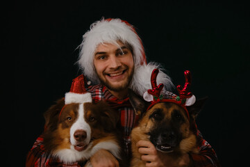 Santa helpers. Concept pets celebrate Christmas and New Year with the owner. Young Caucasian man...