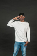 Fototapeta premium An african man with white blank shirt doing a salute pose on the black background