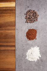 cocoa flour powder and chocolate chips and wooden table on dark marble background