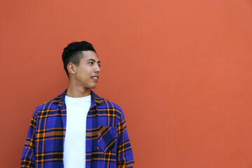Obraz premium Young man of hispanic heritage wearing colorful flannel shirt posing over orange wall. Copy space for text, close up, background.