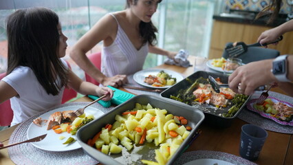 Family eating lunch at home. Mother and daughter seated around food. People gathered together