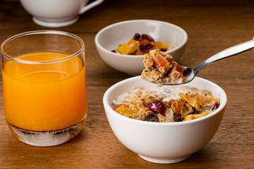 Taking a spoon full of muesli cereal breakfast with fresh milk and preserved sweet tropical fruit...