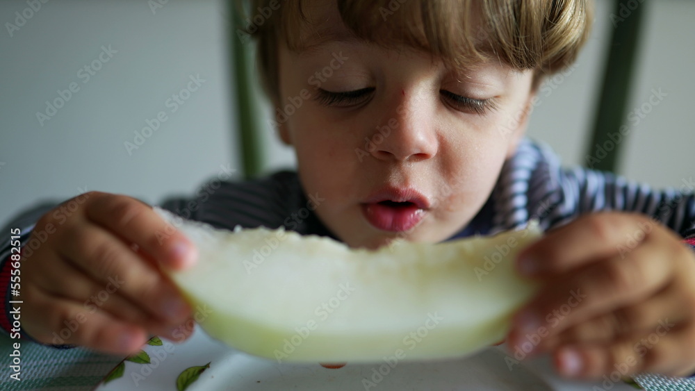 Wall mural Child eating melon fruit hungry little boy eats healthy snack