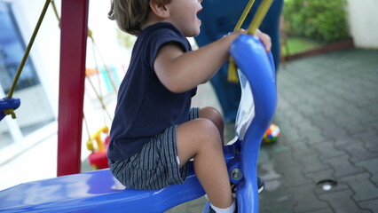 Little boy playing at playground child swinging in movement