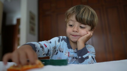 Little boy eating tangerine fruit in the morning wearing pajamas