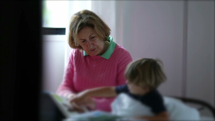 Happy grandmother reading story to grandson. Candid grandma tells bedtime story to little boy grandchild