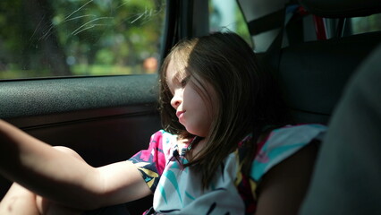 One bored little girl in car backseat waiting. Upset small child in boredom. Kid in traffic