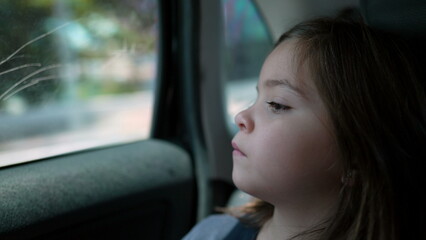 Little girl traveling by car. Child on vacation journey looking at city landscape passing by. Small kid travels by automobile vehicle looking out glass