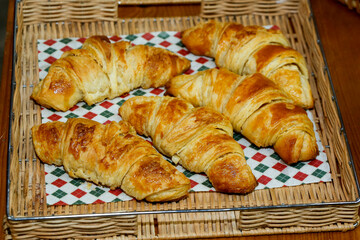 Basket of croissant bread on checkered tablecloth