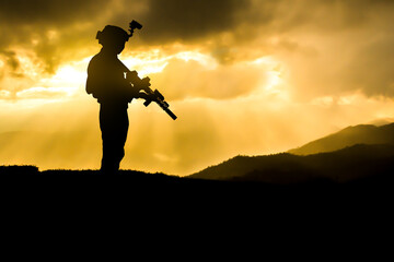 Silhouette of military soldier with assault rifle weapon against a sunset