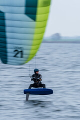 Naklejka premium Hydrofoil Race Kitesurfer with kite in the foreground in cold winter conditions