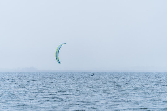 Wide shot of Hydrofoil Kitesurfer with kite in misty winter conditions