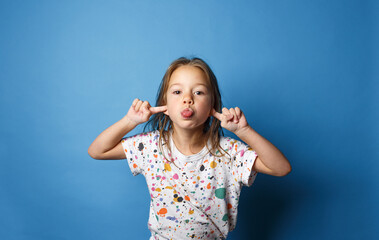 a little girl shows faces and grimaces on a blue background.