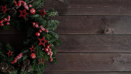 Fototapeta na wymiar Closeup of beautiful Christmas wreath made natural Christmas trees decorated with stars,cones and berries lies on old dark wooden boards,top view,copy space.Christmas and New Year banner.Wreath making