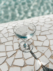 Carbonated mineral water in a wineglass on a sunny day, against the backdrop of a swimming pool. Valencia, Spain. Close-up shot