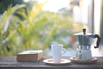 Stainless moka pot and white coffee mug and thick old book