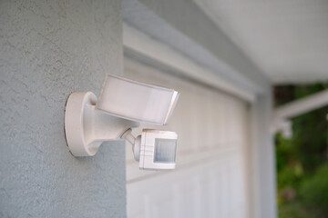 Motion sensor with light detector mounted on exterior wall of private house as part of security system - obrazy, fototapety, plakaty