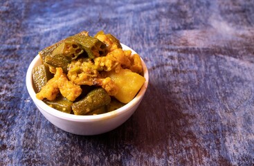 Lady Finger or Okra and Potato Curry or Gravy in  White Bowl Isolated on Blue Background with Copy Space