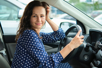 Young stylish woman driver sitting behind steering wheel of her car. Driving vehicle concept