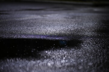 water drops and a puddle on wet pavement at night