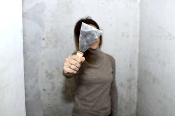 woman showing a scraper in front during renovation or painting work. concept preparing the walls for wallpapering or painting
