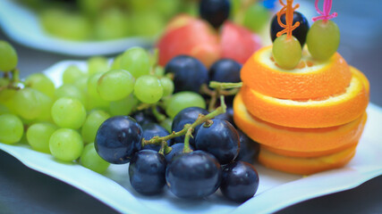 close up.plate with grapes and oranges on blurred background