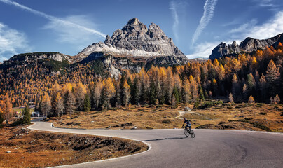 Amazing mountain landscape at autumn sunny day. scenic alpine scenery of Dolomites Alps. Wonderful view on Mountain valley, forest, and asphalt road for majestic rocky peak. travel on bike concept.