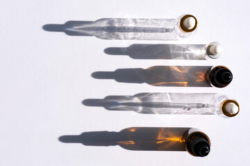 Top view of bottles with essence that cast shadows on a white background. Top view, space for text.