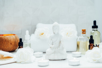Fototapeta na wymiar Spa and wellness massage kit and White Buddha statue. Concept of Asian relaxing spa procedure with essential oils. Alternative medicine and body care. Selective focus. copy space.