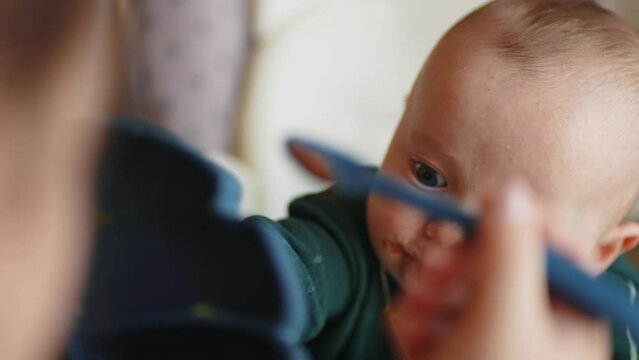 baby newborn eats. dirty mess baby boy eating vegetables. baby son eats on a feeding chair dirty face indoors. naughty dirty babe indulges while feeding. happy kid dream family weaning concept
