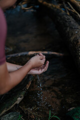 A young female cyclist is washing her hands by the creek