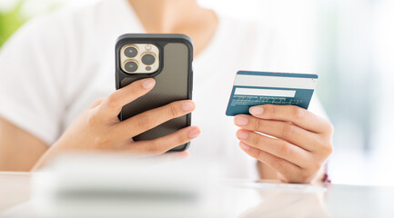 Close up shot of female hand holding credit card and using smartphone for online shopping