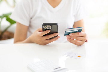 Close up shot of female hand holding credit card and using smartphone for online shopping