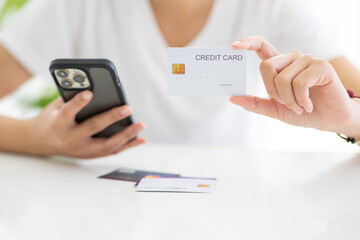 Close up shot of female hand holding credit card and using smartphone for online shopping