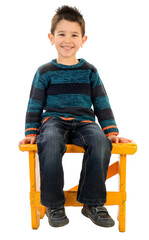 Isolated boy in jeans and striped pullover smiling sitting on a yellow bench. © NATI