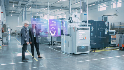 Factory Digitalization: Two Industrial Engineers Use Tablet Computer, Visualize the Wall of Big...
