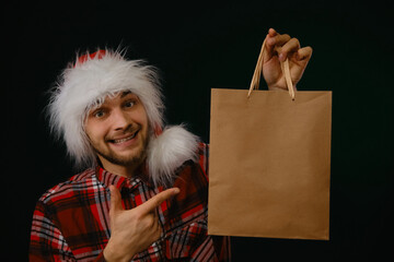 Concept Christmas promotion sale on Black Friday. Young Caucasian man in red fluffy Santa Claus hat...