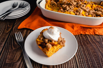 Pumpkin French Toast Casserole Topped with Whipped Cream: Slice of pumpkin French toast breakfast casserole served on a plate