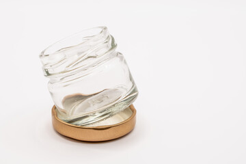 small empty clear glass jar adjacent to a bronze coloured screw down metal lid