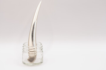 a shiny chrome plated steel knife letter opener standing upright in a clear glass jar 