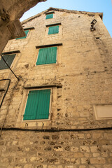 Fototapeta na wymiar Old medieval wall with wooden window shutters in Split in Croatia