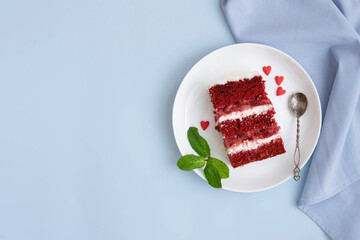 A piece of red velvet sponge cake white plate with hearts, blue background. Festive sweet dessert