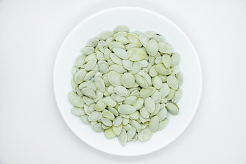 White pumpkin seeds on a white plate. Pumpkin seeds on a white background.