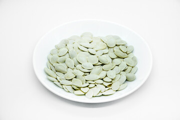 White pumpkin seeds on a white plate. Pumpkin seeds on a white background.