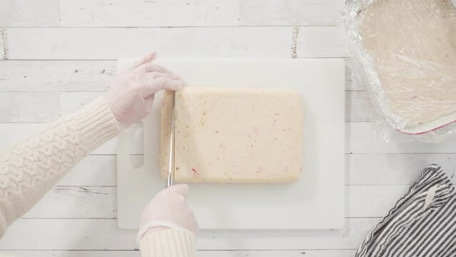 Flat lay. Step by step. Cutting homemade candy cane fudge on a white cutting board.