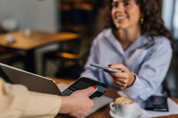 Woman is paying the bill with her smart phone, contactless