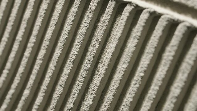 Gray wall glue plaster comb surface prepared for tiling. Tile adhesive notched trowel patterns. Texture background of tile mortar paste. Grey cement wall with a linear pattern. Macro shot.