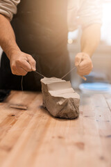 Close up of man cutting clay and making ornament on earthenware.